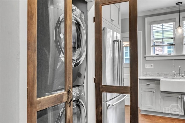 217 E 54th St, Savannah, GA 31405 - laundry area featuring stacked washer / dryer, ornamental molding, and light wood-type flooring