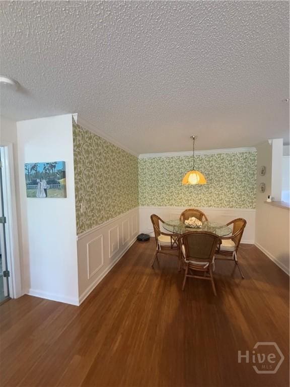 9307 Walden Park Dr, Savannah, GA 31410 - dining room featuring wallpapered walls, a textured ceiling, dark wood-style floors, a wainscoted wall, and ornamental molding