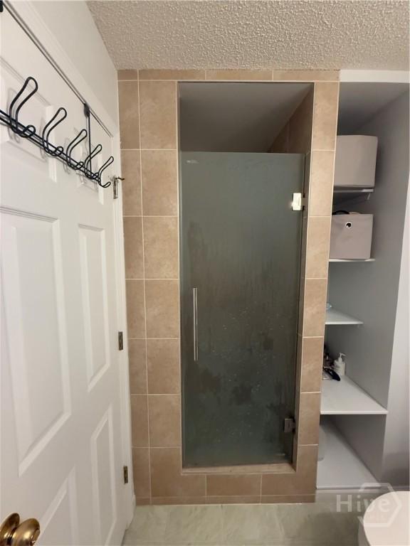 9307 Walden Park Dr, Savannah, GA 31410 - bathroom with a shower stall, a textured ceiling, and tile patterned floors