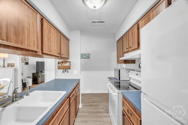 13 Bryan Wood Cir, Savannah, GA 31410 - kitchen with white appliances, under cabinet range hood, a textured ceiling, light wood-style flooring, and a wainscoted wall
