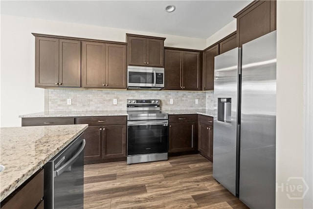 1161 Turpentine Trl, Hinesville, GA 31313 - kitchen with appliances with stainless steel finishes, dark brown cabinetry, decorative backsplash, light stone countertops, and recessed lighting