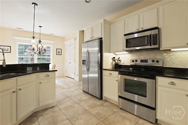 72 Roswell Trl, Richmond Hill, GA 31324 - kitchen featuring stainless steel appliances, a chandelier, dark countertops, decorative light fixtures, and a wainscoted wall