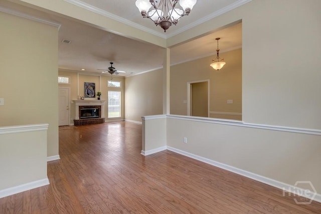 633 Greenwich Dr, Richmond Hill, GA 31324 - unfurnished living room featuring wood finished floors, crown molding, a chandelier, ceiling fan, and a fireplace