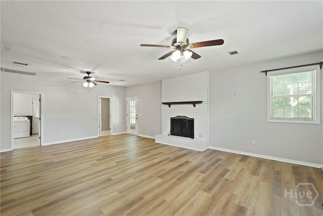265 Mahan St, Jesup, GA 31545 - unfurnished living room with washer / dryer, ceiling fan, light wood finished floors, a textured ceiling, and a fireplace
