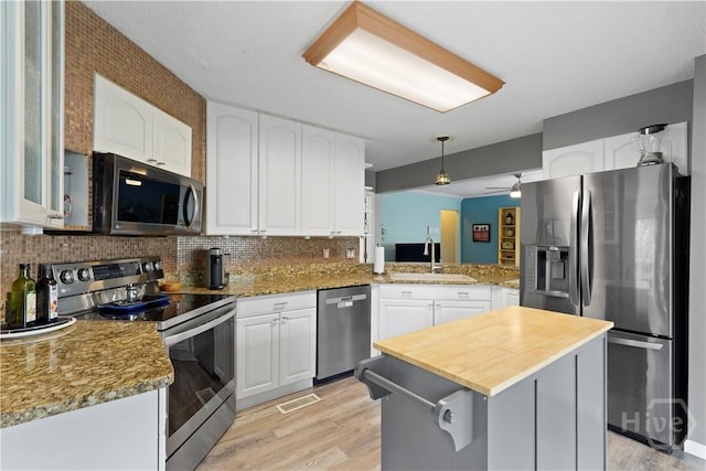 505 Pointe N Dr, Savannah, GA 31410 - kitchen with stainless steel appliances, light wood-style flooring, wood counters, tasteful backsplash, and white cabinets