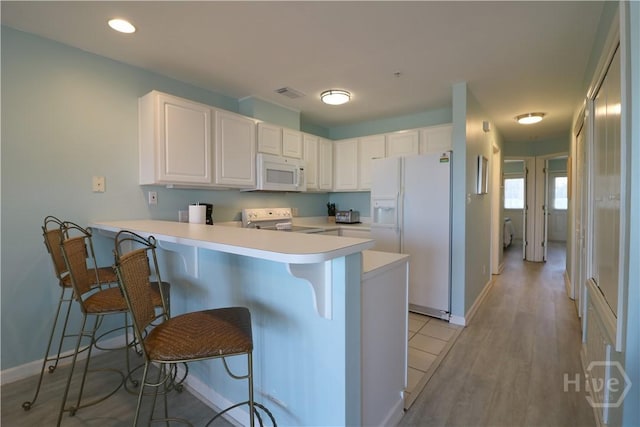 1615 Strand Ave Unit 4, Tybee Island, GA 31328 - kitchen featuring white appliances, a peninsula, a kitchen breakfast bar, light countertops, and white cabinetry