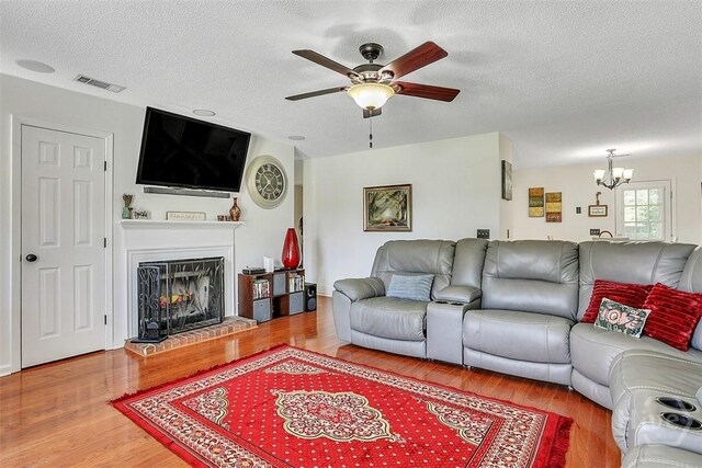 198 Jennifer Cir, Rincon, GA 31326 - living room with ceiling fan, wood finished floors, a chandelier, a textured ceiling, and a fireplace with raised hearth