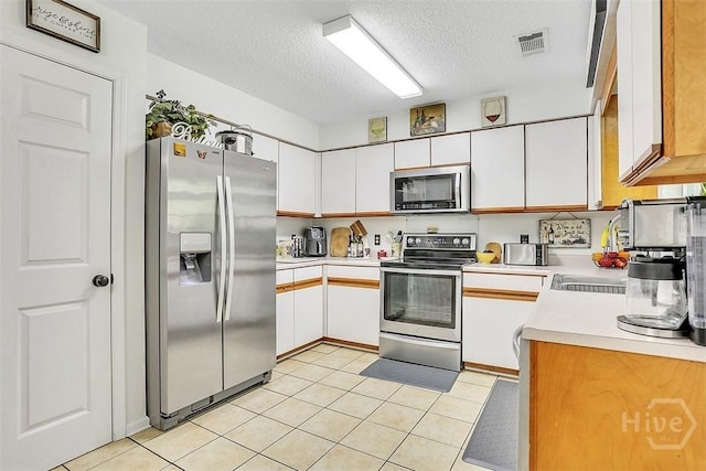 198 Jennifer Cir, Rincon, GA 31326 - kitchen featuring appliances with stainless steel finishes, light countertops, a textured ceiling, white cabinets, and light tile patterned floors