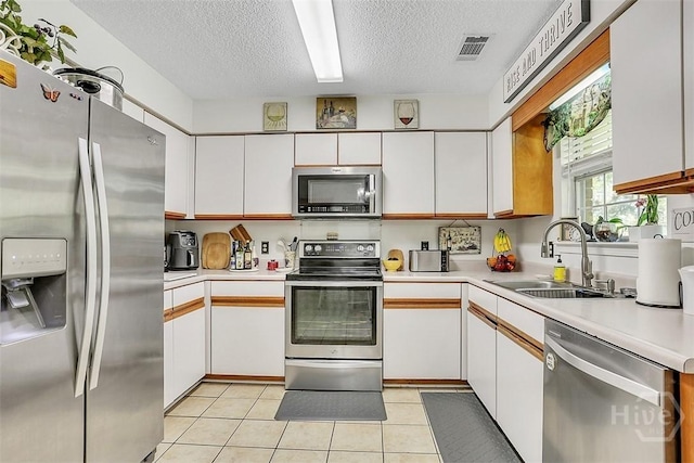 198 Jennifer Cir, Rincon, GA 31326 - kitchen with stainless steel appliances, a textured ceiling, white cabinets, light countertops, and light tile patterned floors