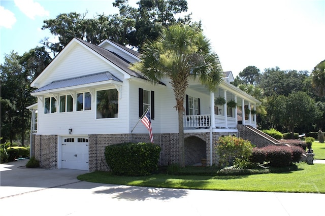 2766 Fort Mcallister Rd, Richmond Hill, GA 31324 - view of front of property featuring a garage, concrete driveway, covered porch, and brick siding