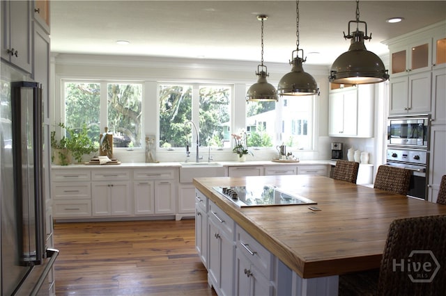 2766 Fort Mcallister Rd, Richmond Hill, GA 31324 - kitchen with appliances with stainless steel finishes, wooden counters, wood finished floors, pendant lighting, and white cabinetry