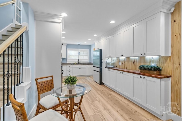 115 Coquena Cir E, Savannah, GA 31410 - kitchen with stainless steel refrigerator, light wood-style flooring, white cabinets, recessed lighting, and decorative light fixtures