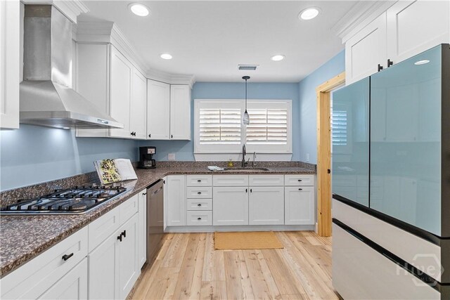 115 Coquena Cir E, Savannah, GA 31410 - kitchen with wall chimney exhaust hood, appliances with stainless steel finishes, white cabinets, light wood-type flooring, and dark stone counters