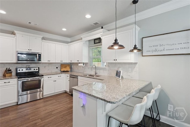 105 Summer Station Dr, Guyton, GA 31312 - kitchen with stainless steel appliances, ornamental molding, white cabinets, dark wood-style floors, and a peninsula