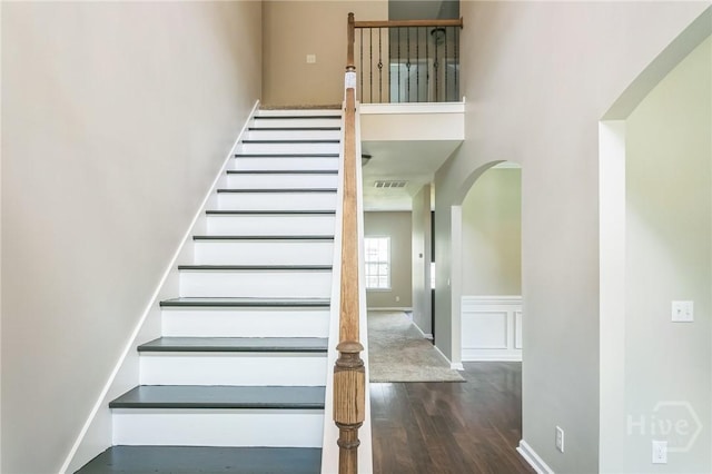 804 Barrington Dr, Hinesville, GA 31313 - stairway with arched walkways, wood finished floors, a towering ceiling, and a wainscoted wall