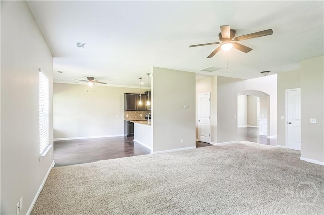 804 Barrington Dr, Hinesville, GA 31313 - unfurnished living room with ceiling fan, dark carpet, arched walkways, and plenty of natural light