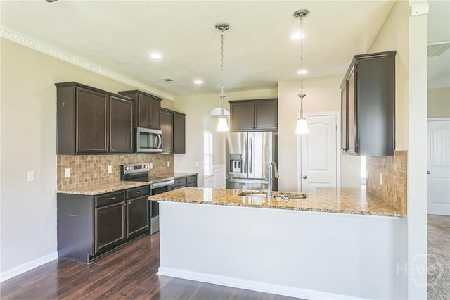 804 Barrington Dr, Hinesville, GA 31313 - kitchen featuring appliances with stainless steel finishes, dark brown cabinets, light stone countertops, a peninsula, and decorative backsplash
