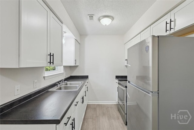 1021 Walnut Ct, Springfield, GA 31329 - kitchen featuring appliances with stainless steel finishes, dark countertops, light wood-style floors, white cabinetry, and a textured ceiling
