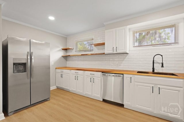 13 Hughes Ave, Savannah, GA 31406 - kitchen with stainless steel appliances, light wood-style floors, backsplash, ornamental molding, and white cabinets