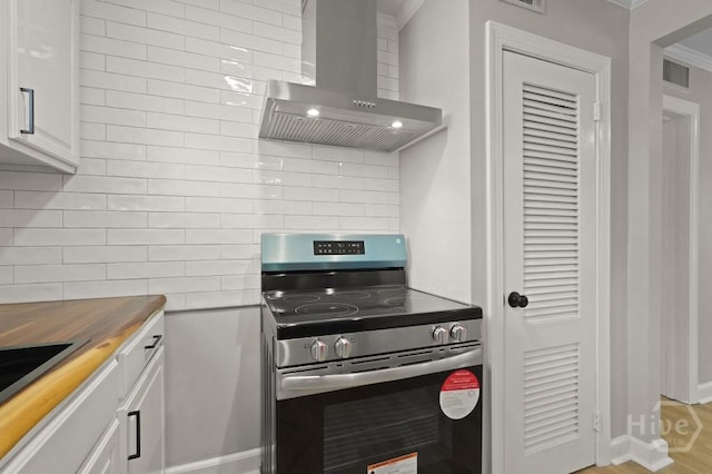13 Hughes Ave, Savannah, GA 31406 - kitchen featuring electric stove, wall chimney range hood, tasteful backsplash, butcher block countertops, and white cabinetry