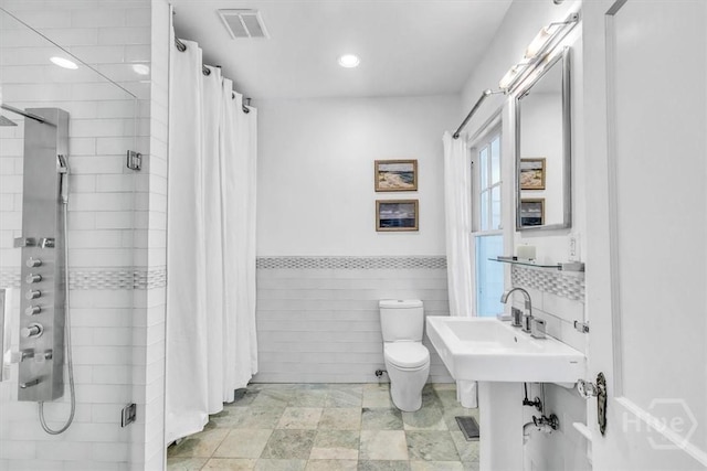 1226 E 50th St, Savannah, GA 31404 - full bathroom featuring a stall shower, tile walls, recessed lighting, and a wainscoted wall