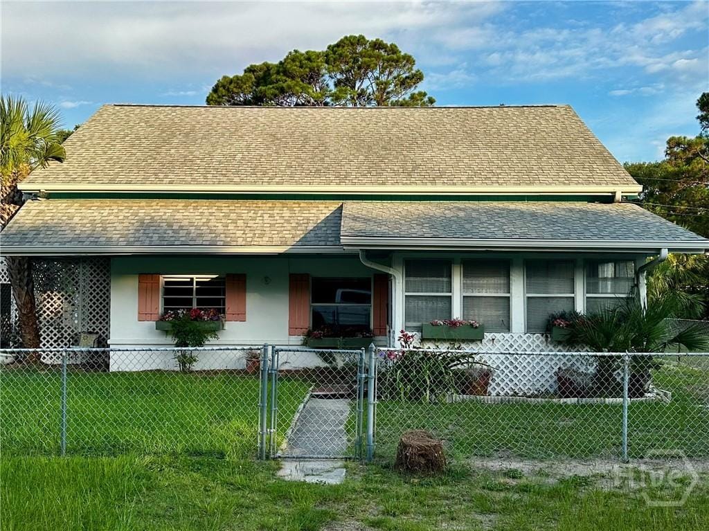 9 Miller Ave, Tybee Island, GA 31328 - view of front of home with a fenced front yard, roof with shingles, and a gate