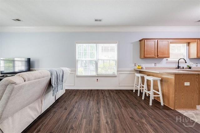 86 Fellwood Dr, Rincon, GA 31326 - kitchen featuring crown molding, dark wood-type flooring, light countertops, brown cabinets, and a breakfast bar