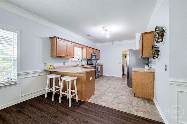 86 Fellwood Dr, Rincon, GA 31326 - kitchen featuring appliances with stainless steel finishes, a peninsula, ornamental molding, light countertops, and brown cabinetry