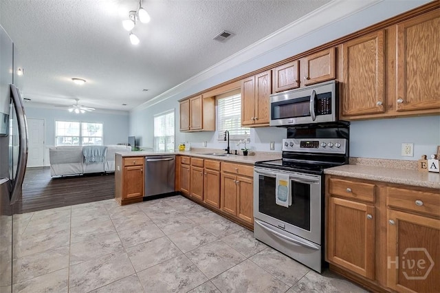 86 Fellwood Dr, Rincon, GA 31326 - kitchen featuring appliances with stainless steel finishes, crown molding, brown cabinetry, open floor plan, and light countertops