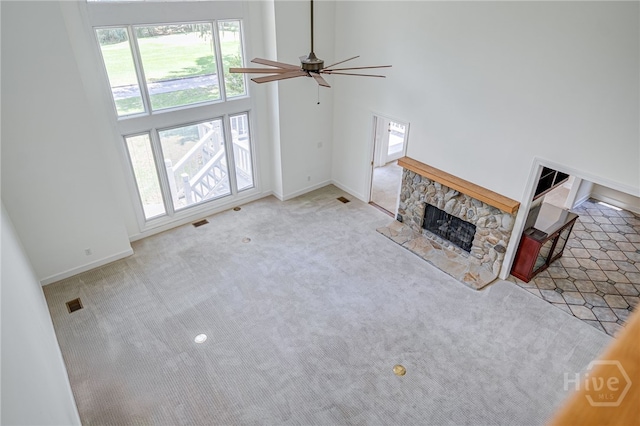 1 Hobcaw Ln, Savannah, GA 31411 - unfurnished living room featuring a ceiling fan, carpet flooring, a stone fireplace, and a high ceiling