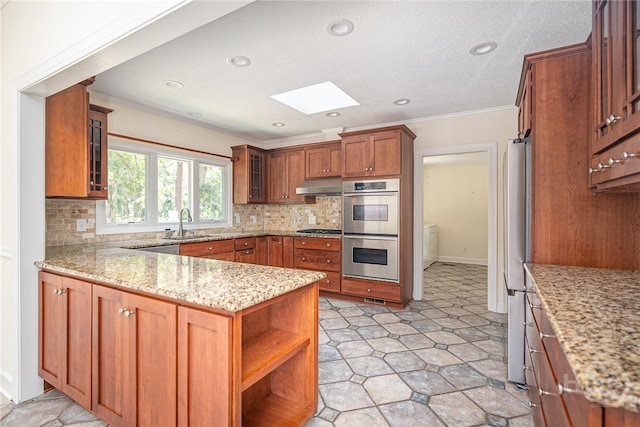1 Hobcaw Ln, Savannah, GA 31411 - kitchen featuring a skylight, stainless steel appliances, a peninsula, brown cabinets, and light stone counters