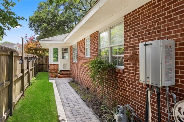 540 E 60th St, Savannah, GA 31405 - view of side of property with entry steps, brick siding, tankless water heater, a fenced backyard, and crawl space