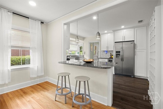 540 E 60th St, Savannah, GA 31405 - kitchen with stainless steel refrigerator with ice dispenser, a breakfast bar area, wood finished floors, white cabinetry, and recessed lighting