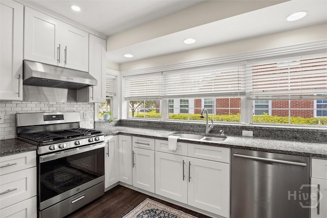 540 E 60th St, Savannah, GA 31405 - kitchen featuring appliances with stainless steel finishes, under cabinet range hood, white cabinets, dark wood-style floors, and dark stone counters