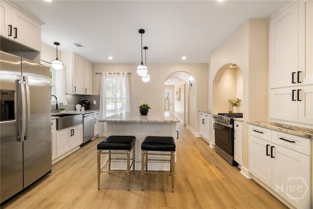 402 E 57th St, Savannah, GA 31405 - kitchen featuring stainless steel appliances, a center island, arched walkways, light wood-style floors, and recessed lighting