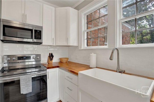 1406 E 50th St, Savannah, GA 31404 - kitchen with appliances with stainless steel finishes, wooden counters, backsplash, and white cabinetry