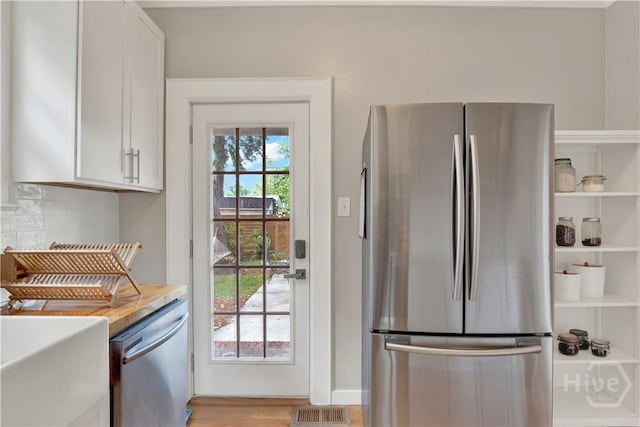1406 E 50th St, Savannah, GA 31404 - kitchen with appliances with stainless steel finishes, white cabinets, light countertops, backsplash, and light wood-style floors
