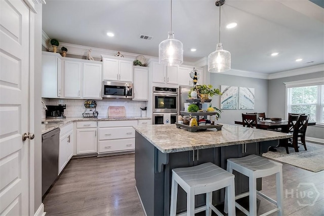 1652 Belle Island Rd, Richmond Hill, GA 31324 - kitchen with appliances with stainless steel finishes, ornamental molding, a kitchen breakfast bar, decorative backsplash, and a center island