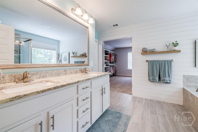 1652 Belle Island Rd, Richmond Hill, GA 31324 - full bath featuring wood finished floors, a stall shower, plenty of natural light, double vanity, and wood walls