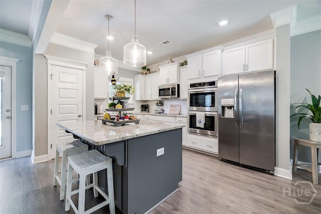 1652 Belle Island Rd, Richmond Hill, GA 31324 - kitchen with appliances with stainless steel finishes, white cabinets, crown molding, a kitchen island, and light wood-style floors