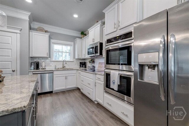 1652 Belle Island Rd, Richmond Hill, GA 31324 - kitchen with appliances with stainless steel finishes, ornamental molding, recessed lighting, decorative backsplash, and white cabinetry