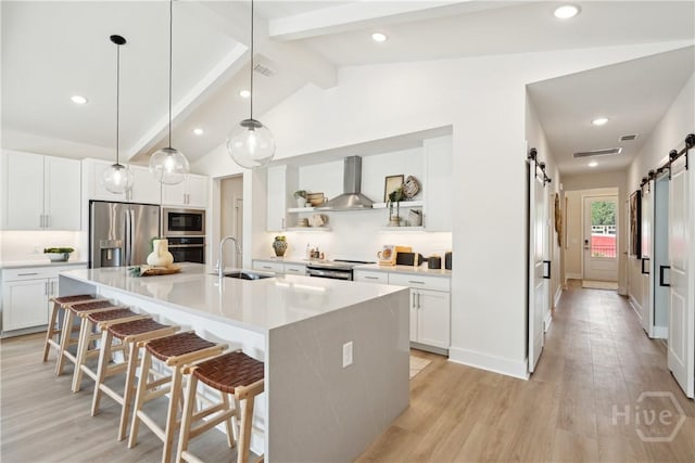 117 Mage St, Savannah, GA 31302 - kitchen with appliances with stainless steel finishes, wall chimney exhaust hood, a barn door, open shelves, and a breakfast bar
