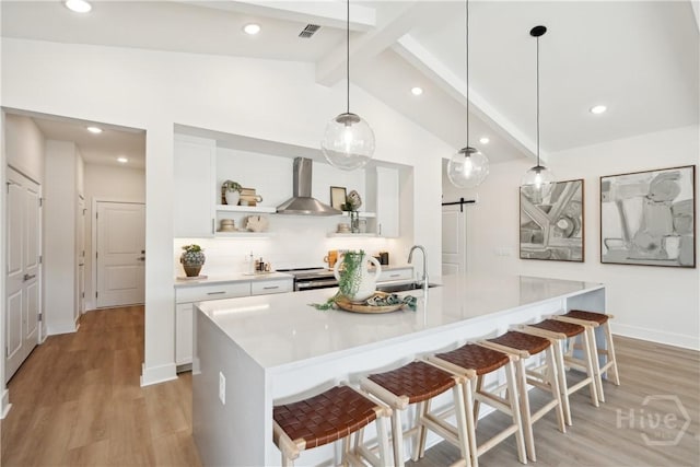 117 Mage St, Savannah, GA 31302 - kitchen with wall chimney range hood, open shelves, light wood finished floors, a breakfast bar area, and white cabinetry