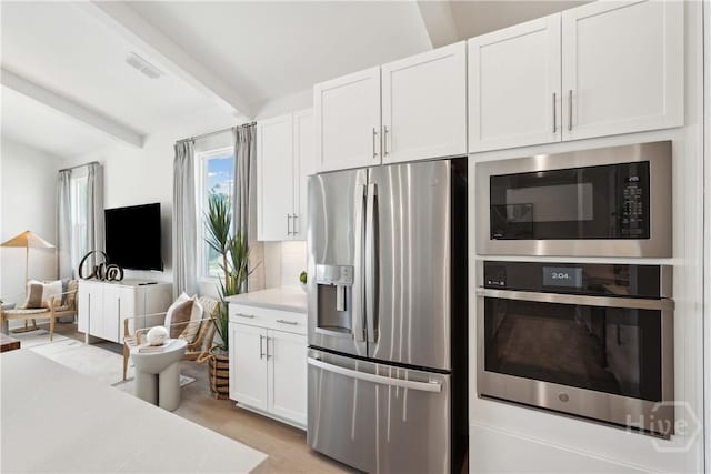 117 Mage St, Savannah, GA 31302 - kitchen featuring appliances with stainless steel finishes, light countertops, white cabinets, beamed ceiling, and light wood-type flooring