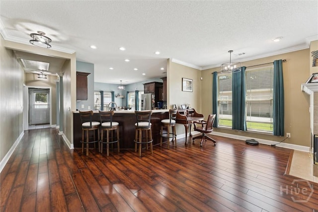 25 Savannah Ln, Richmond Hill, GA 31324 - kitchen featuring stainless steel fridge, a textured ceiling, a peninsula, dark wood finished floors, and a kitchen breakfast bar
