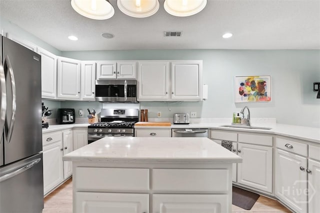 144 Summer Winds Dr, Savannah, GA 31410 - kitchen with appliances with stainless steel finishes, light wood finished floors, white cabinetry, a center island, and recessed lighting