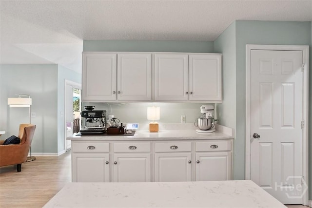 144 Summer Winds Dr, Savannah, GA 31410 - kitchen with light wood-type flooring, white cabinetry, a textured ceiling, and light stone countertops