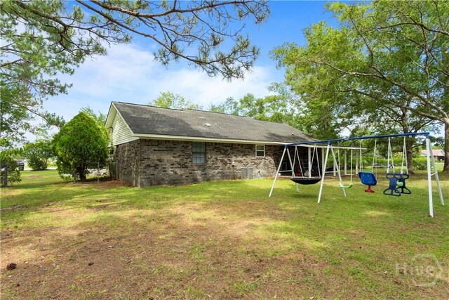 65 Fabian Ln, Hinesville, GA 31313 - back of house with a playground, a lawn, and brick siding