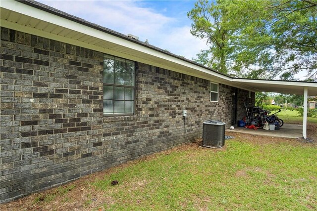 65 Fabian Ln, Hinesville, GA 31313 - view of side of home with an attached carport, a lawn, and brick siding