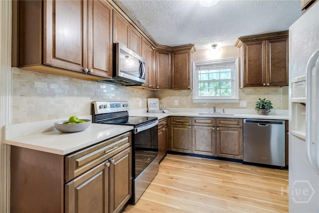 322 Suncrest Blvd, Savannah, GA 31410 - kitchen featuring stainless steel appliances, light wood-type flooring, light countertops, tasteful backsplash, and a textured ceiling